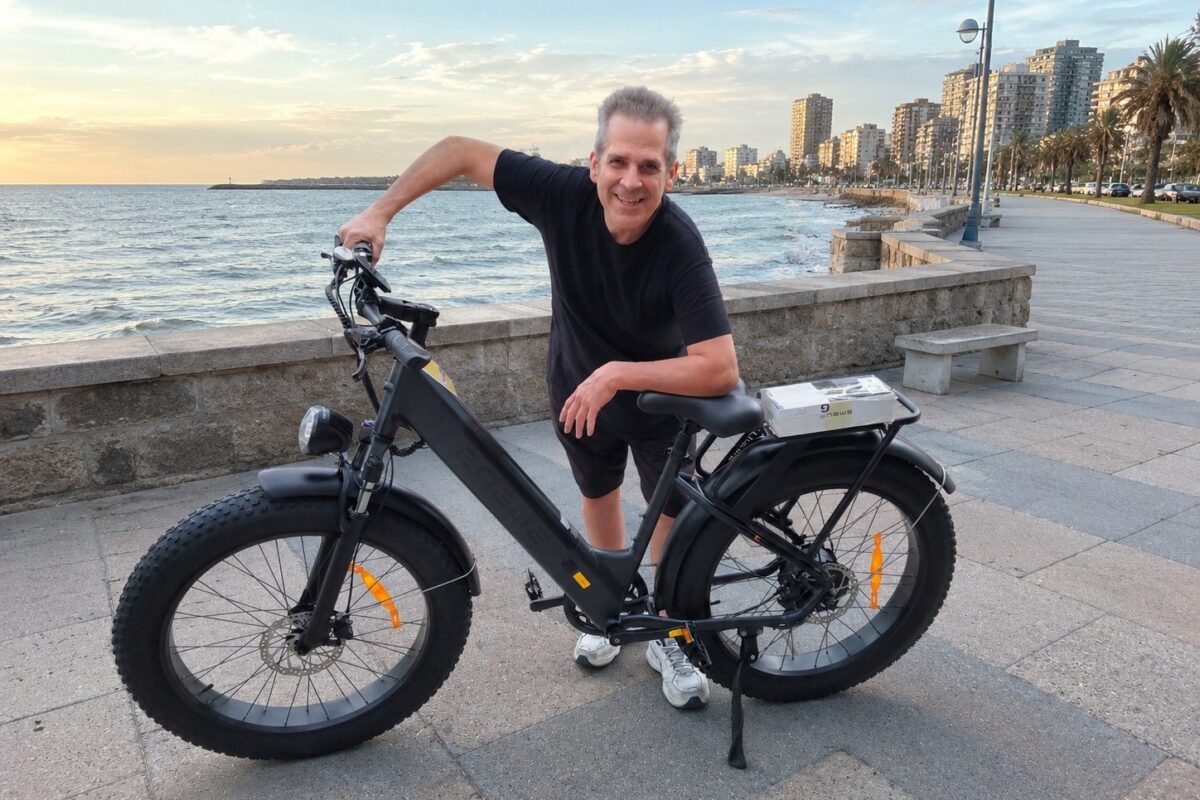 Hombre de más de 40 años sonriendo junto a su bicicleta eléctrica ENGWE en la costanera