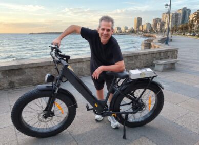 Hombre de más de 40 años sonriendo junto a su bicicleta eléctrica ENGWE en la costanera