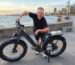 Hombre de más de 40 años sonriendo junto a su bicicleta eléctrica ENGWE en la costanera