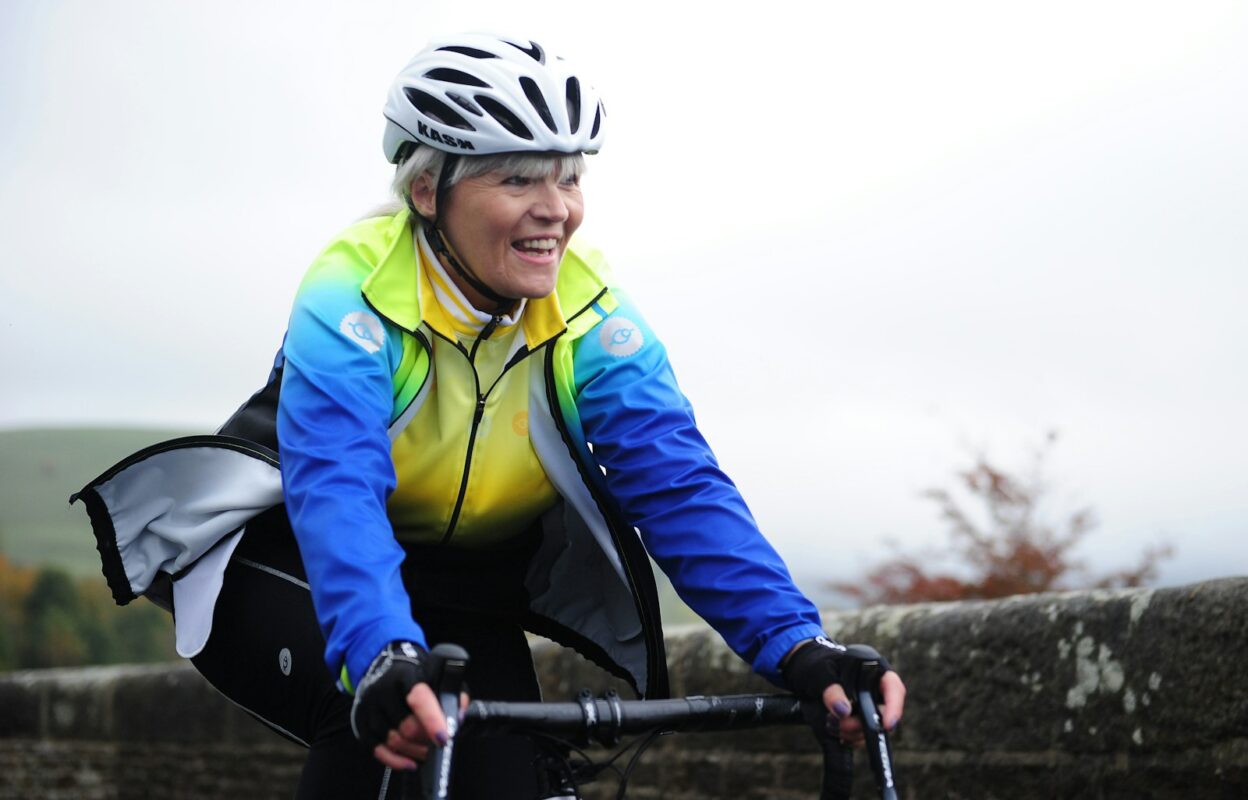 Ciclismo después de los 40 Mujer de más de 40 años sonriendo mientras pedalea al aire libre