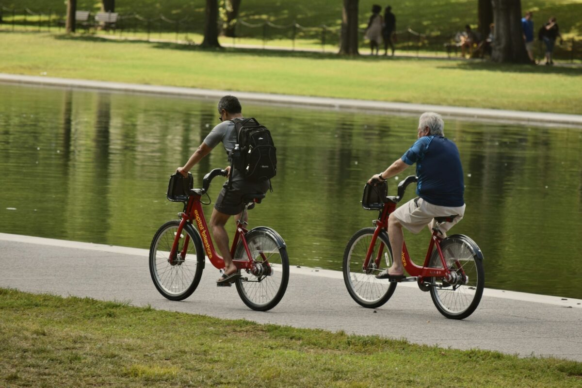 Pedalear a tu ritmo Dos hombres pedaleando tranquilos junto a un lago en un parque